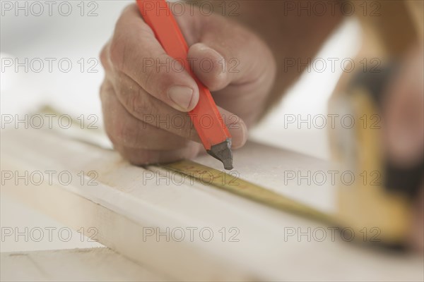 Caucasian carpenter measuring lumber