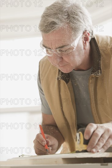 Caucasian carpenter measuring lumber