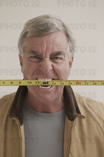 Caucasian carpenter biting measuring tape