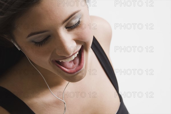 Mixed race woman listening to headphones and singing