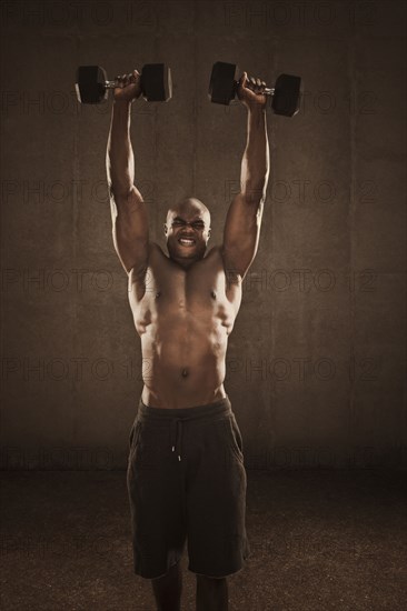 Grimacing African American man lifting weights