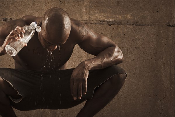 African American man pouring water over himself after exercise
