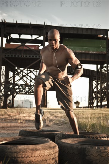 Black man running through tire obstacle course