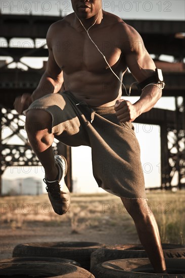 Black man running through tire obstacle course