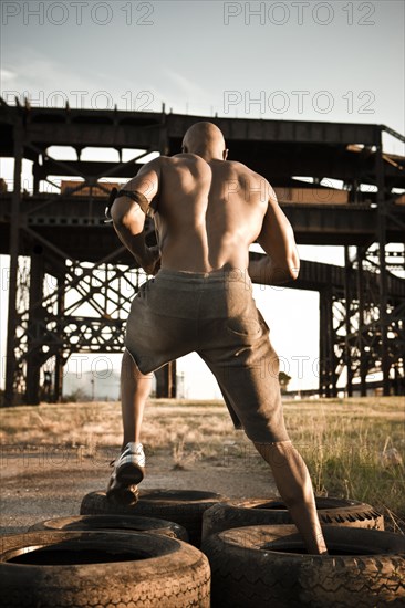 Black man running through tire obstacle course