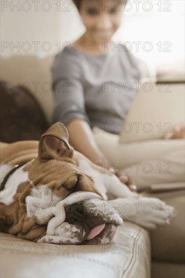 Native American woman sitting on sofa with English bulldog