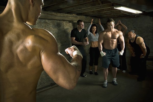 People watching two men boxing without gloves