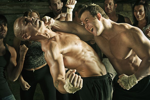 People watching boxer hitting opponent on the jaw