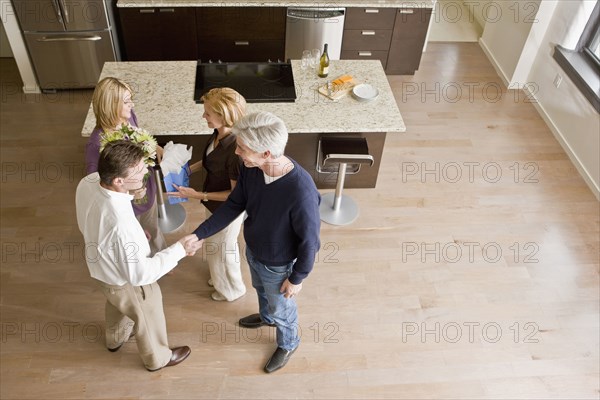 Caucasian friends talking together in modern kitchen