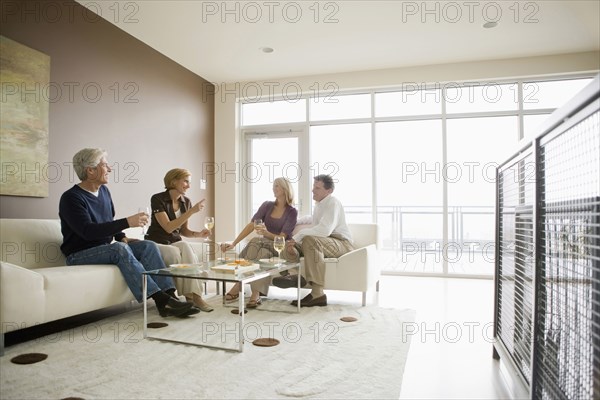 Caucasian couples drinking wine in modern living room