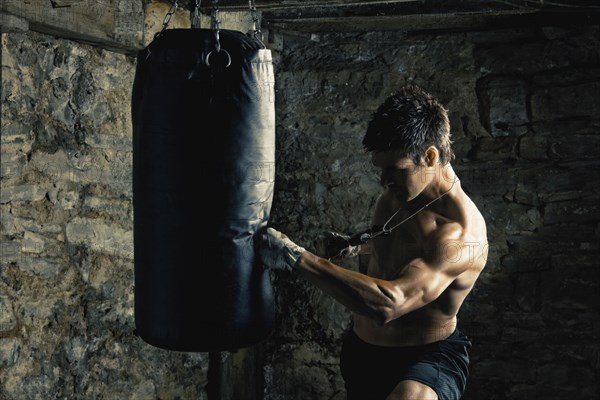 Caucasian boxer training and hitting punching bag