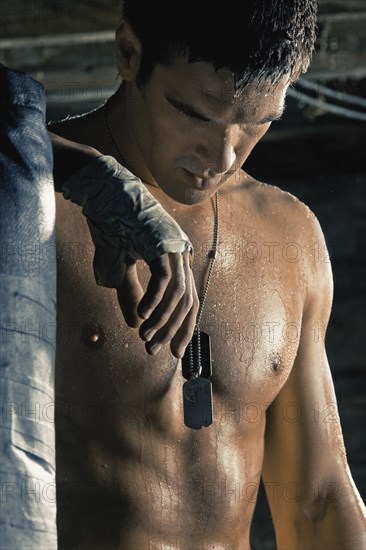 Caucasian boxer with taped hands leaning on punching bag