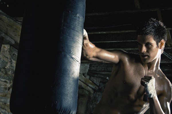 Caucasian boxer training and hitting punching bag