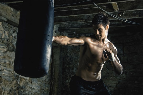 Caucasian boxer training and hitting punching bag