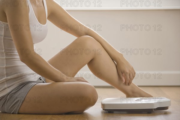 Caucasian woman sitting on floor near scale