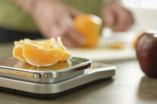 Senior woman weighing orange on scale