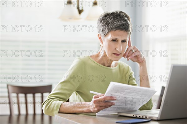 Senior woman paying bills on laptop