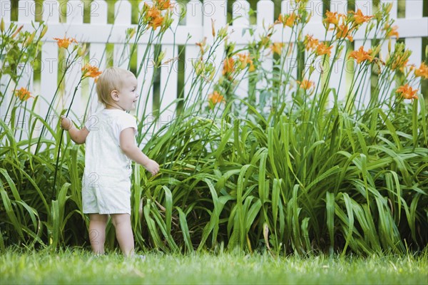 Caucasian girl exploring flowers in backyard