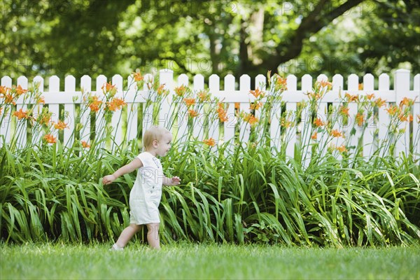 Caucasian girl exploring flowers in backyard