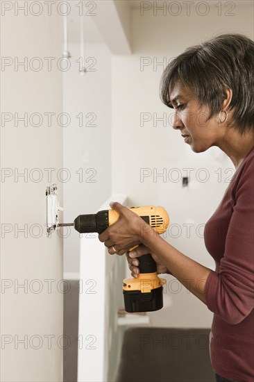 Mixed race woman using cordless drill