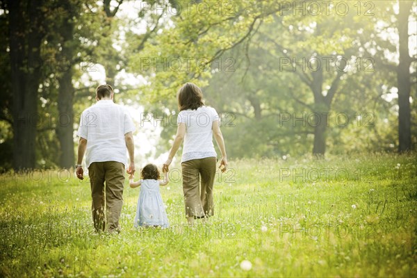 Parents walking with daughter in field