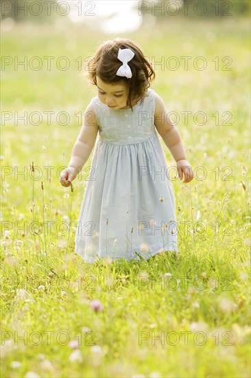 Caucasian girl picking flowers in field