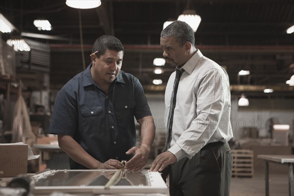 Businessman talking to worker in warehouse