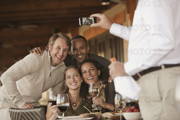 Man taking photographs of friends in restaurant