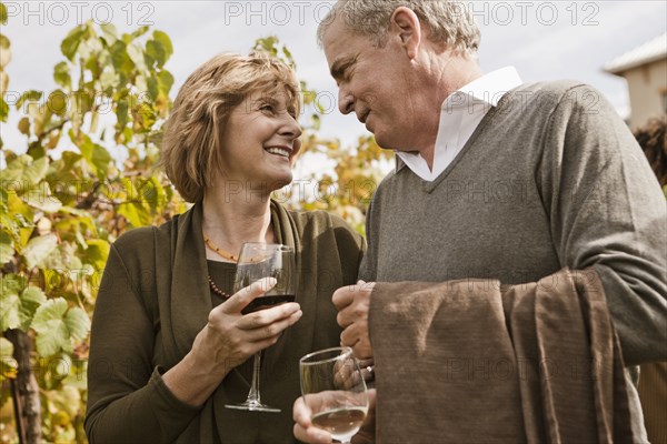 Caucasian couple drinking wine in vineyard