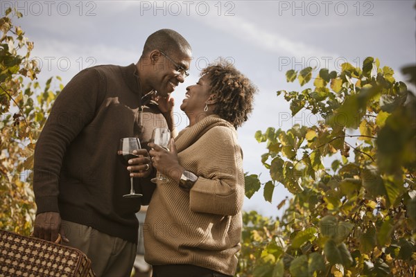 Black couple drinking wine in vineyard