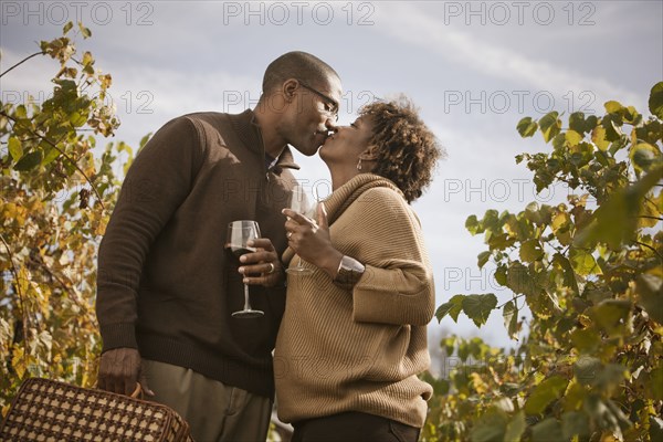 Black couple drinking wine in vineyard