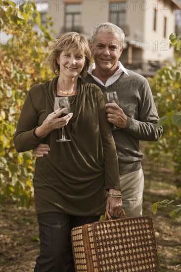 Caucasian couple drinking wine in vineyard