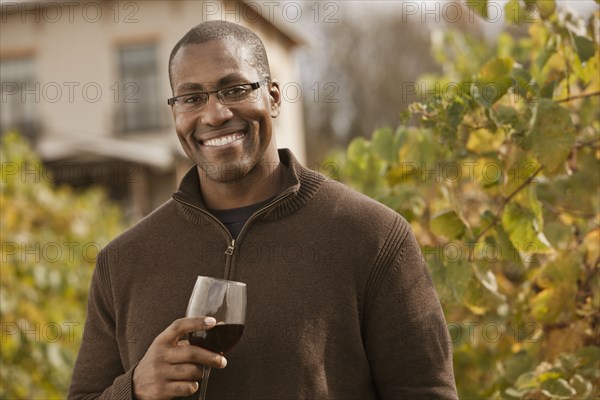 Black man drinking wine in vineyard