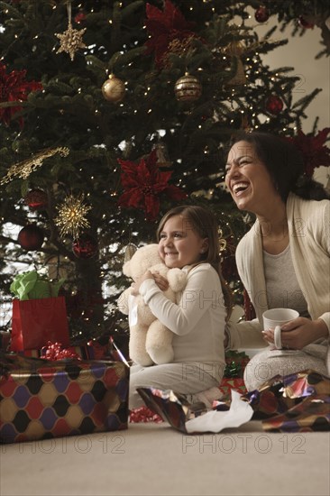 Mixed race mother and daughter opening gifts Christmas morning