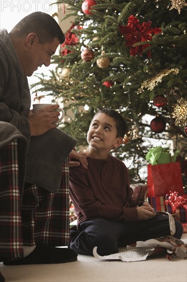 Hispanic father and son opening gifts Christmas morning