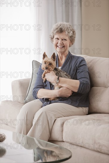 Caucasian woman sitting on sofa holding dog