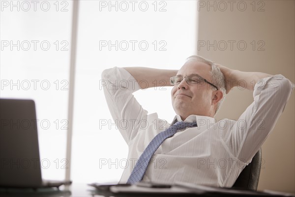 Caucasian businessman sitting at desk with hands on head