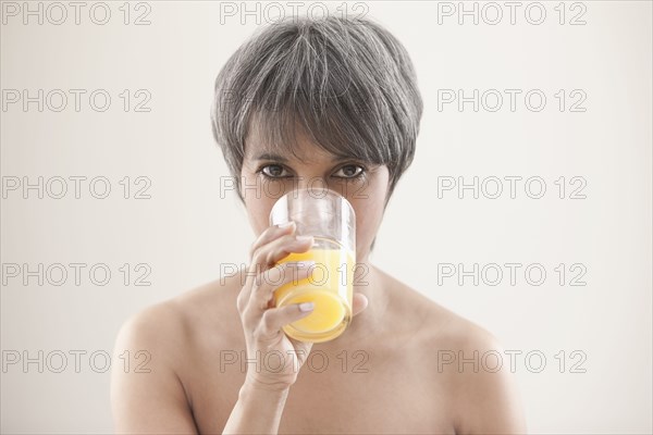 Mixed race woman drinking orange juice