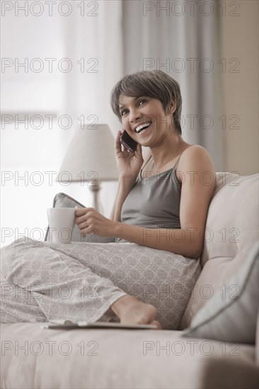 Mixed race woman on sofa talking on cell phone