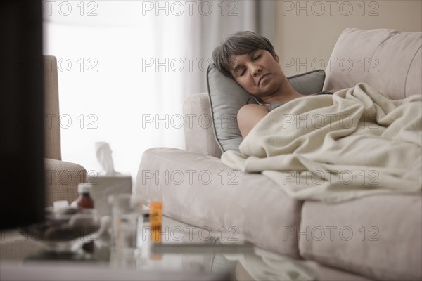 Sick mixed race woman laying on sofa