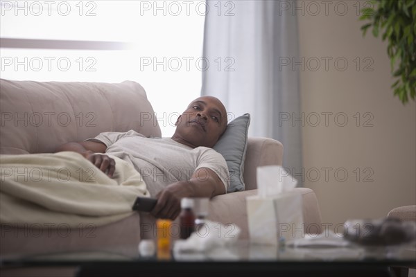 Sick Black man laying on sofa