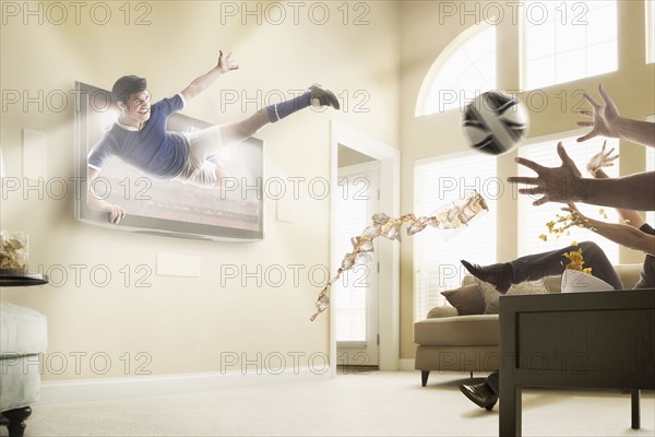 Caucasian soccer player coming out of television set