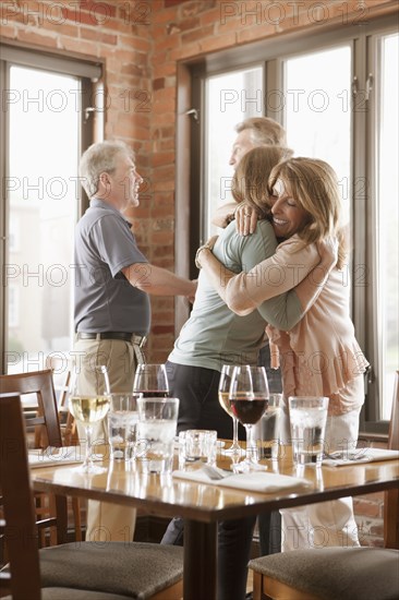 Caucasian friends hugging in restaurant
