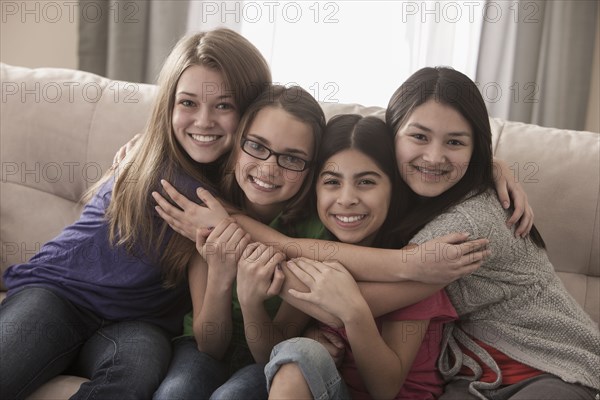 Friends sitting on sofa hugging