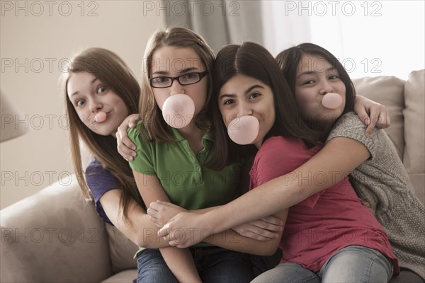 Friends sitting on sofa chewing bubble gum