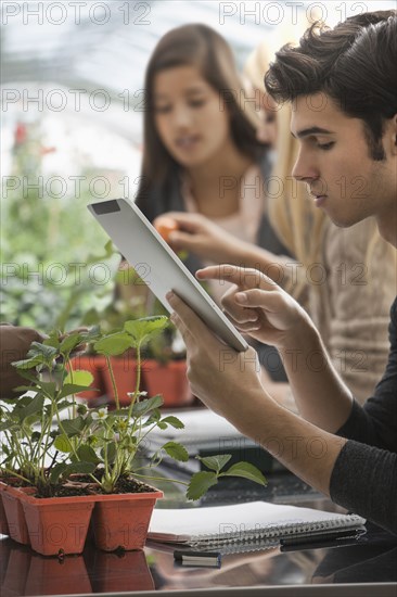 Students working in greenhouse with digital tablet