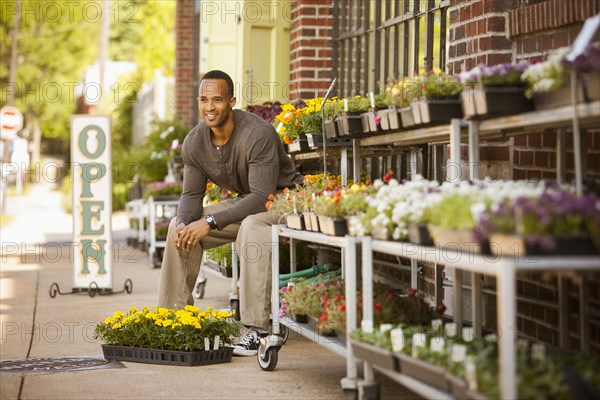 African American man sitting with flowers at flower shop