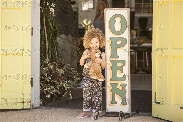 Mixed race girl standing near flower shop open sign