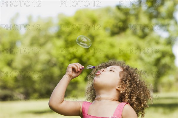 Mixed race girl blowing bubbles