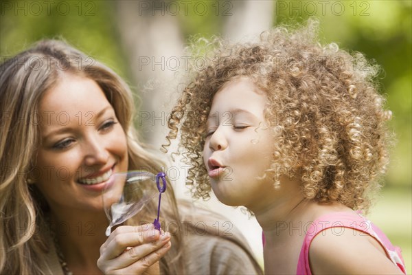 Mother and daughter blowing bubbles